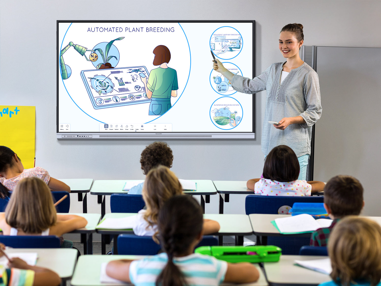 Teacher presenting a STEM lesson on automated plant breeding using a smart board in a modern K-12 classroom