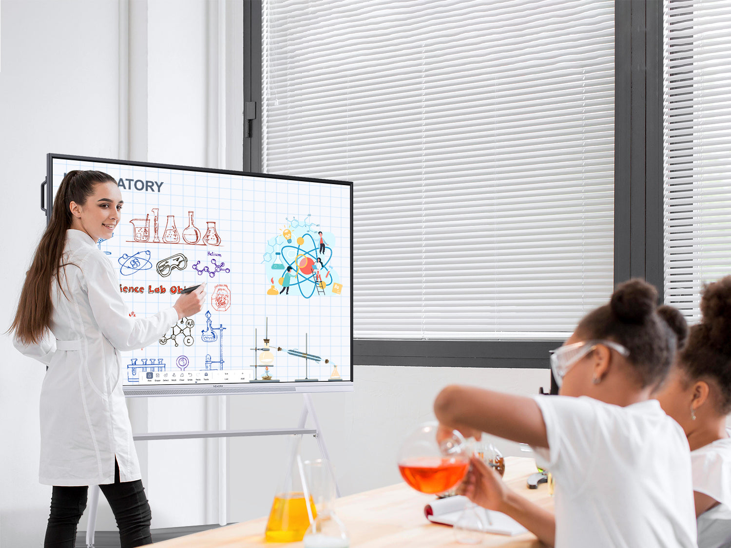 Teacher using a smart board to teach a science experiment while K-12 students conduct hands-on lab activities